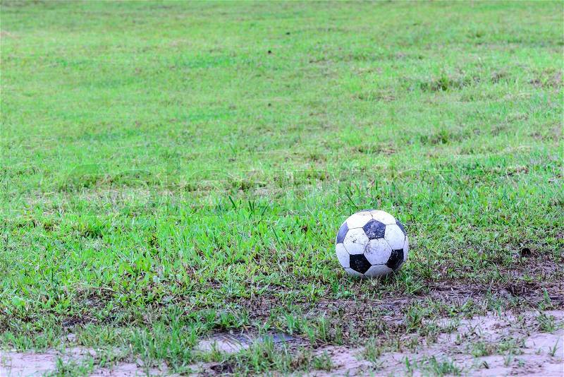 Dirty soccer ball in wet field, stock photo