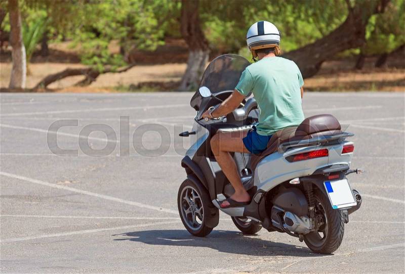Man on three-wheel scooter. View from the back, stock photo