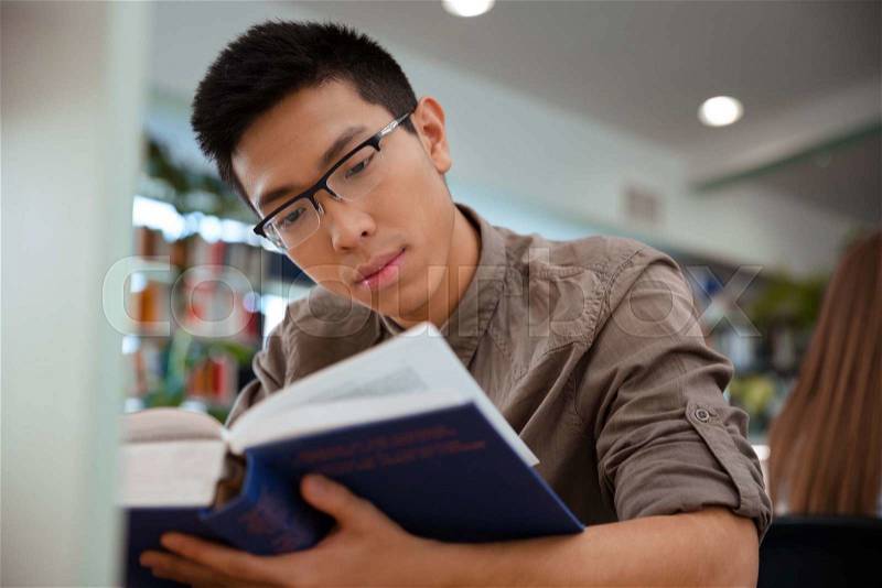 Portrait of a handsome asian male student reading book in university, stock photo