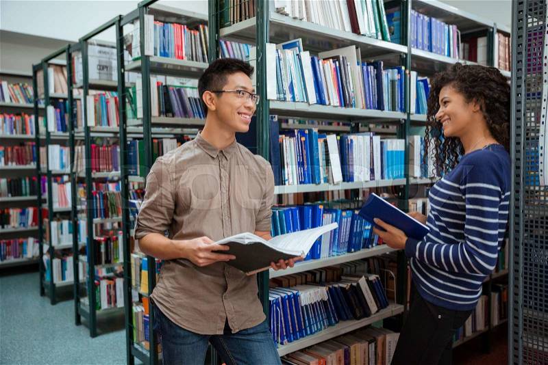Portrait of a happy students speaking in library , stock photo