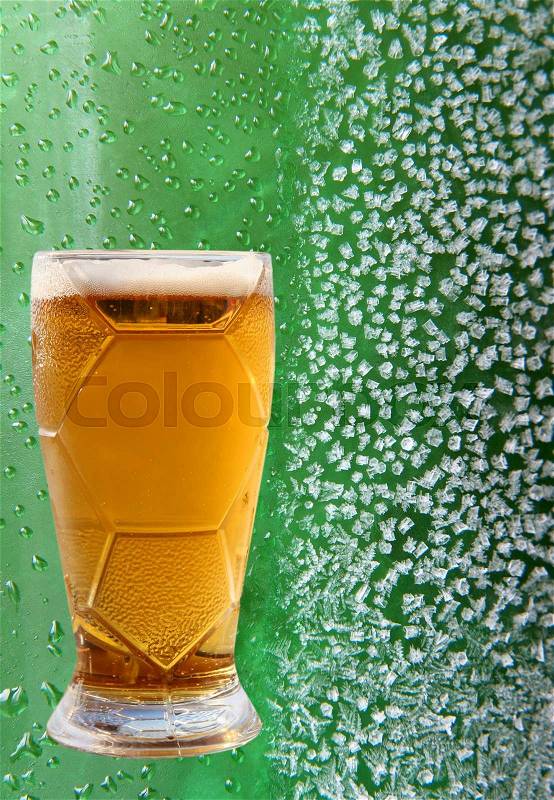 Froth beer glass on ice crystals and drips green background, stock photo