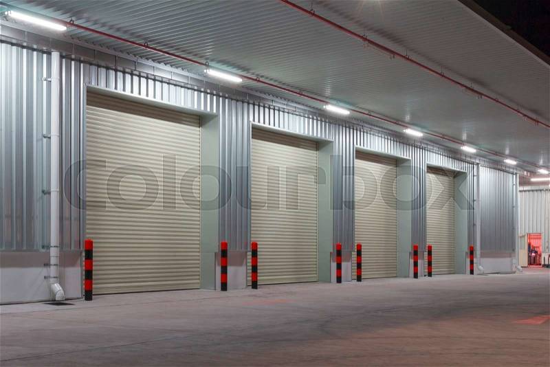 Exterior of factory with shutter door, night time, stock photo