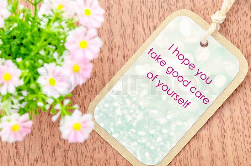 Take care of yourself greeting card with pink flower on wooden background, stock photo