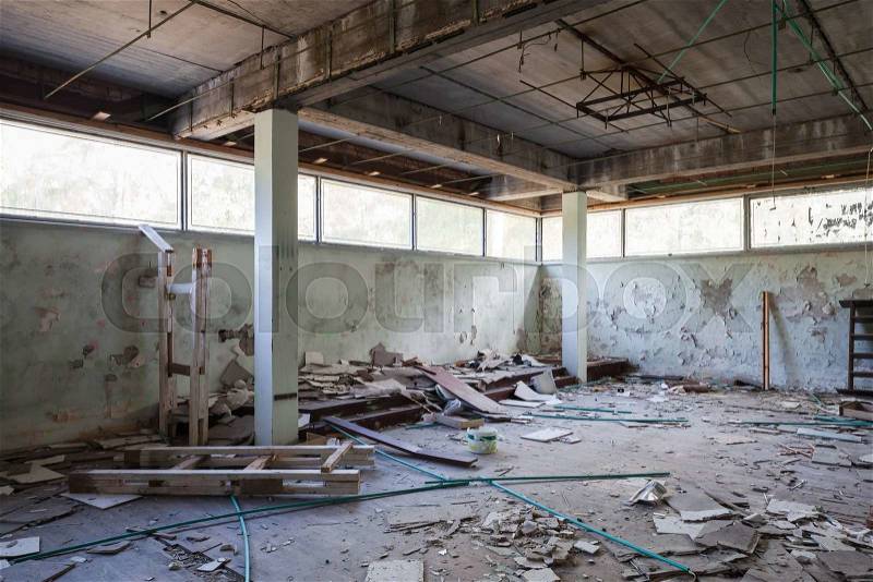 Abandoned industrial building interior. Hall with concrete columns and broken windows, stock photo