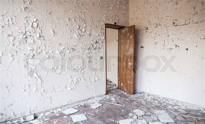 Abandoned industrial building interior. Cracked paint on walls and open wooden door, stock photo