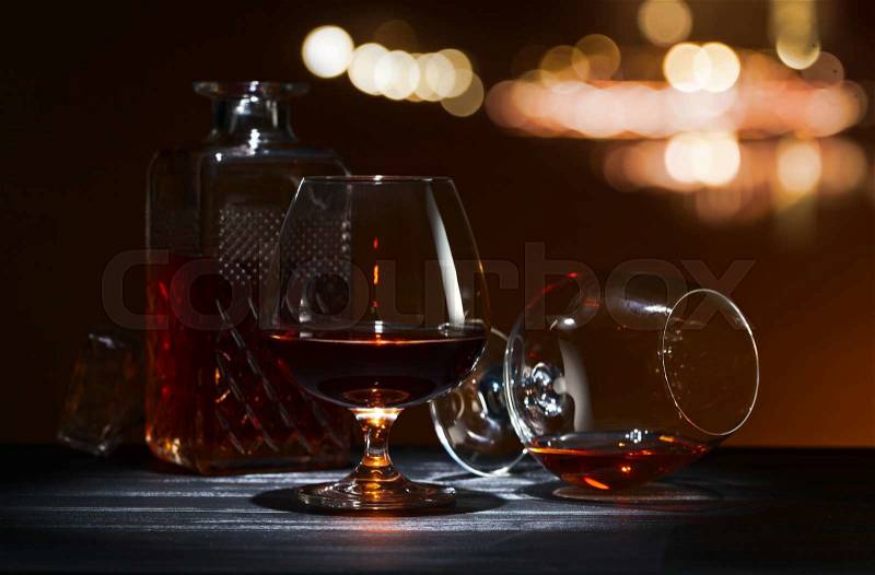 Snifter with brandy on black wooden table, stock photo