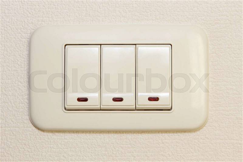 Threefold multiply light switch on beige wall taken closeup, stock photo