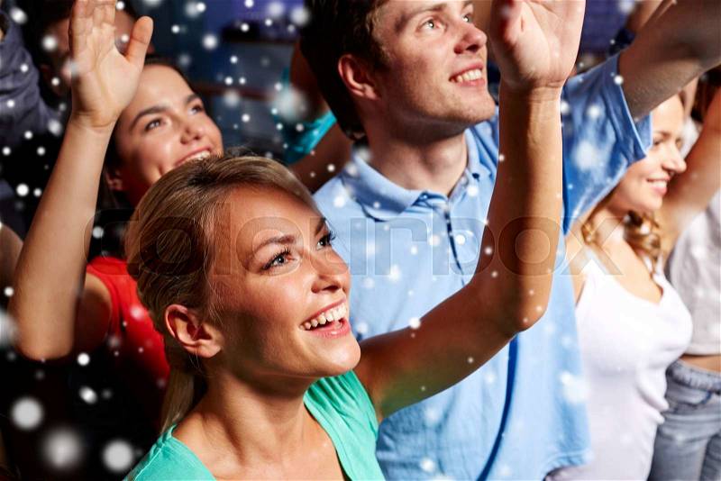 Party, holidays, celebration, nightlife and people concept - smiling friends waving hands at concert in club and snow effect, stock photo