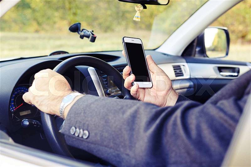 Man looking at the phone while driving his car, stock photo