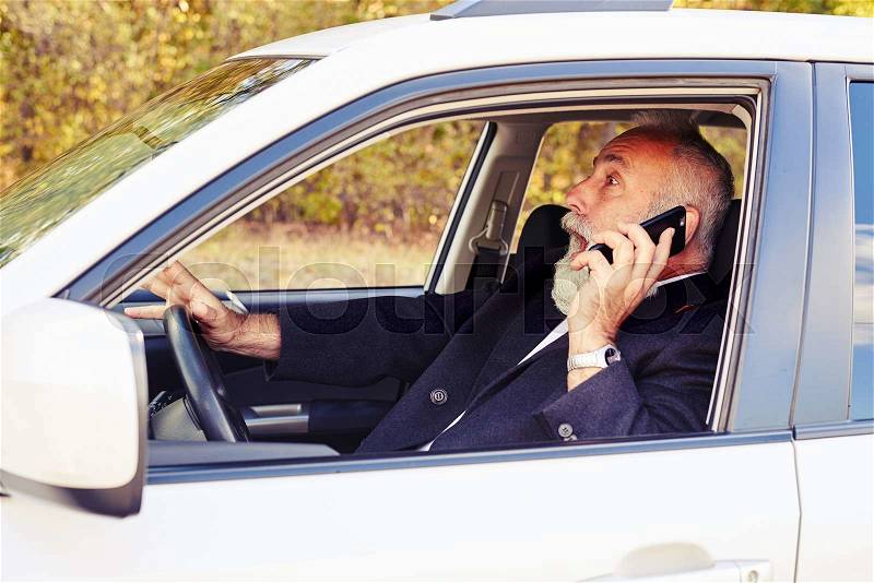 Startled screaming man holding smartphone and driving his car , stock photo