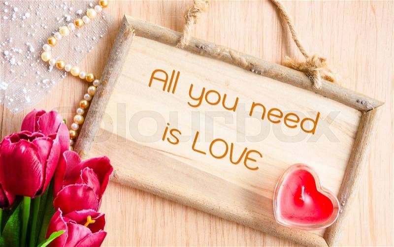 All you need is love. Clock and red tulip with red candle heart shape on wooden background, stock photo