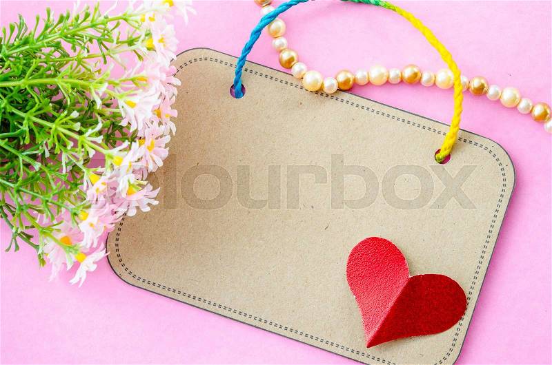 Blank brown paper tag and red heart paper with flower on pink background, stock photo