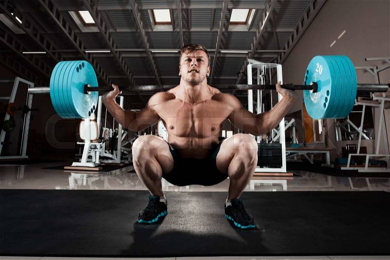 Man at the gym. Execute exercise squatting with weight, in gym, stock photo