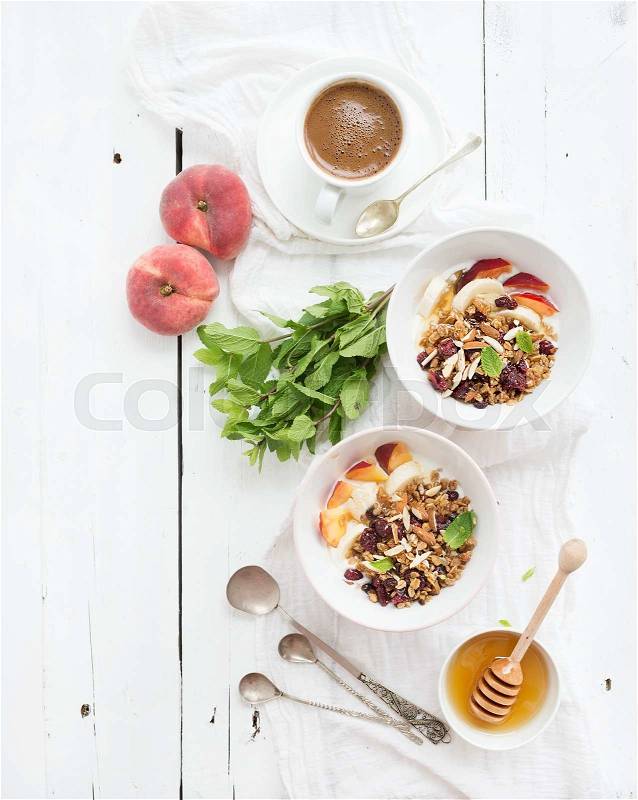 Healthy breakfast. Bowl of oat granola with yogurt, fresh fruit, mint and honey. Cup of coffee, vintage silverware. Top view, copy space, stock photo