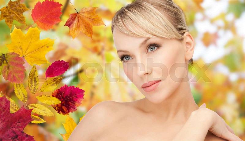 Beauty, people, season and health concept - beautiful young woman face over autumn leaves background, stock photo