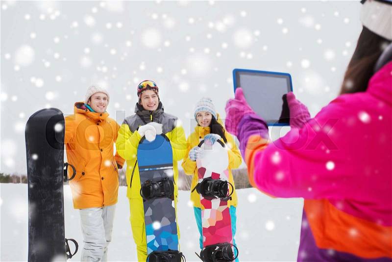 Winter sport, technology, leisure, friendship and people concept - happy friends with snowboards and tablet pc computer taking picture outdoors, stock photo
