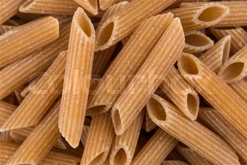 Wholemeal Pasta Penne as close-up shot for background, stock photo