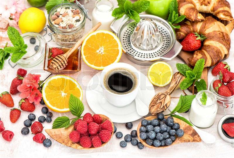 Breakfast with coffee, croissants, granola, honey, fresh berries, fruits orange, apple, milk. Healthy food concept. Selective focus, stock photo