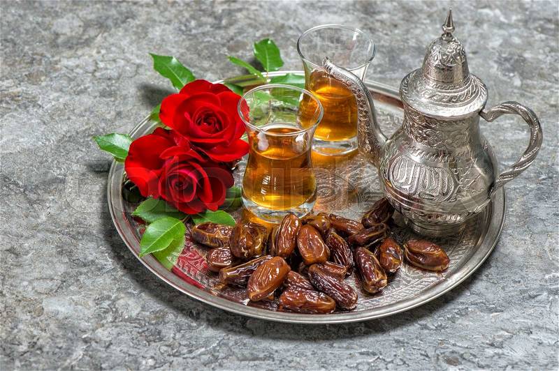 Tea, dates fruits and red rose flowers. Islamic holidays decoration. Ramadan kareem. Eid mubarak. Oriental hospitality concept. Slective focus, stock photo