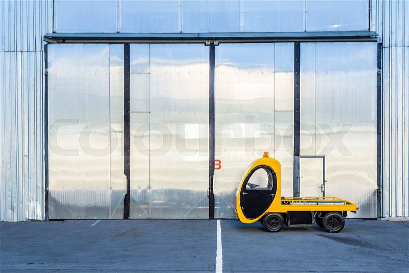 Electric cargo car pickup truck with cargo platform near hangar at the aviation territory. Airfield airport special equipment Forklift. Mini electric cargo truck, stock photo