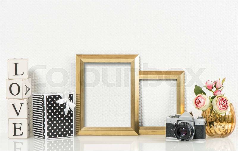 Golden picture frames, rose flowers and no name vintage camera. Retro style decorations with space for your photo or text. Product presentation mock up, stock photo