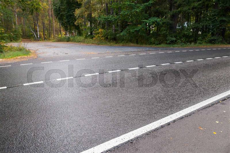 Wet rural asphalt road with striped dividing line, stock photo