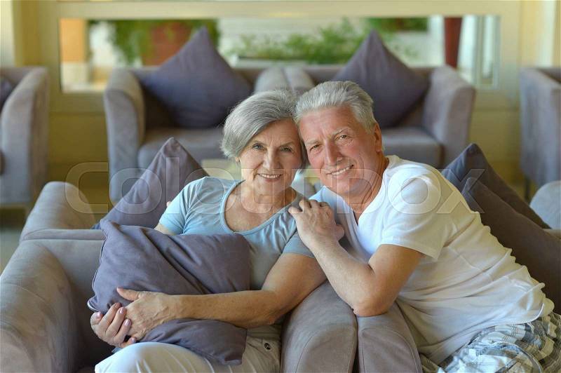 Portrait of beautiful elderly couple on sofa, stock photo