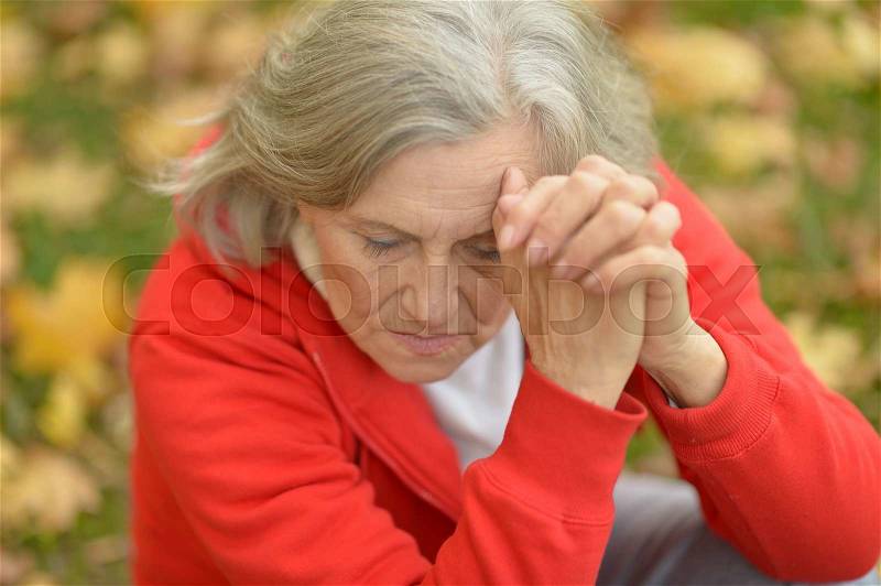 Nice sad old woman on the autumn background, stock photo