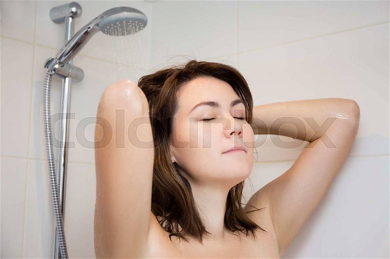 Young beautiful woman washing hair in shower, stock photo