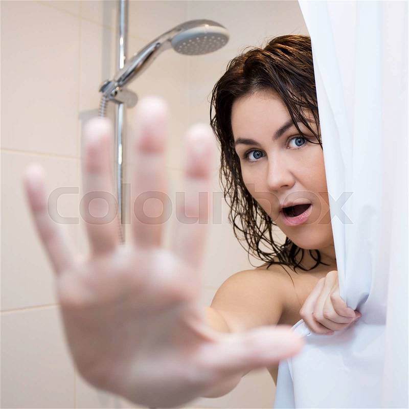 Pretty woman hiding behind curtain in shower, stock photo