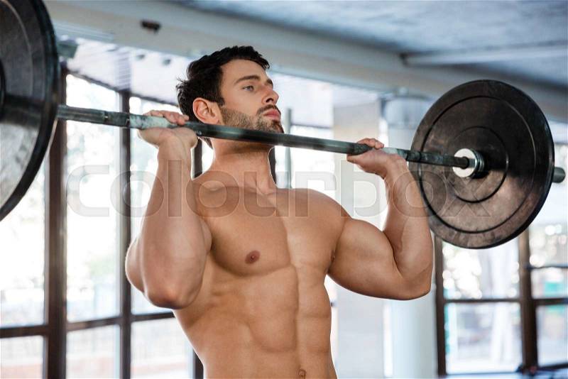 Portrait of a muscular man workout with barbell in gym, stock photo