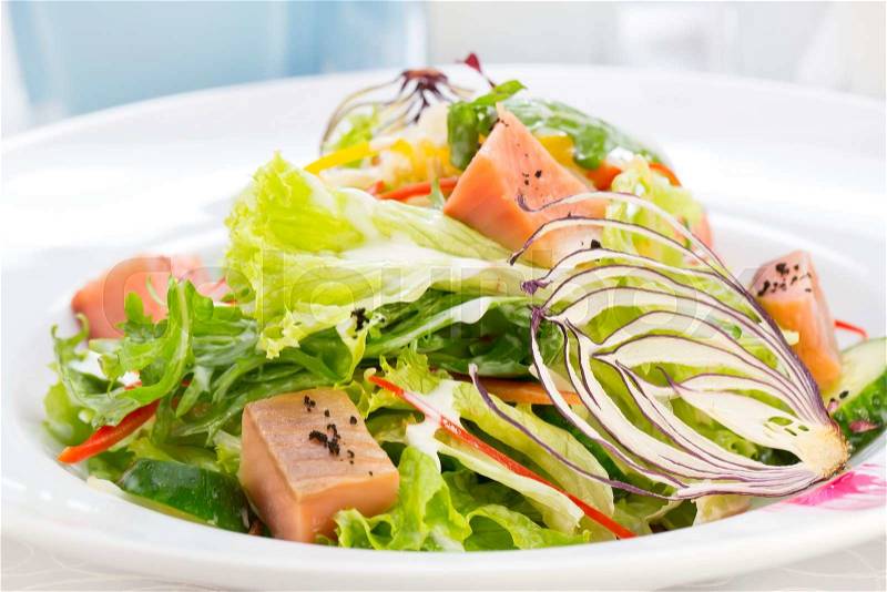 Pink salmon salad and vegetables on a table in a restaurant, stock photo