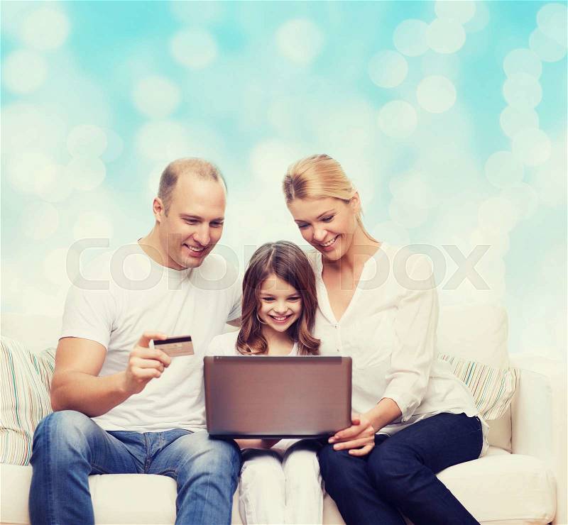 Family, holidays, shopping, technology and people concept - happy family with laptop computer and credit card over blue lights background, stock photo