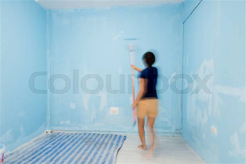 Motion blur woman painting wall in blue, stock photo