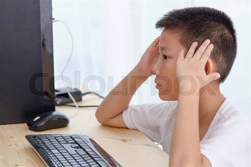 Asian boy playing pc game at home, stock photo
