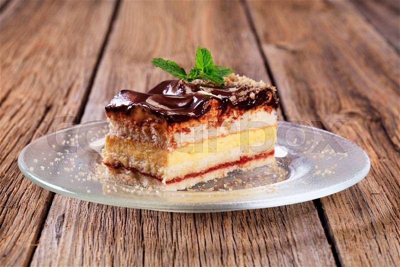 Slice of vanilla cream cake with chocolate icing, stock photo