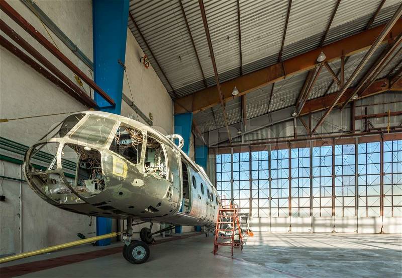 Disassembled helicopter in repair stand in the air hangar. Aircraft without internal details, seats and trim, stock photo
