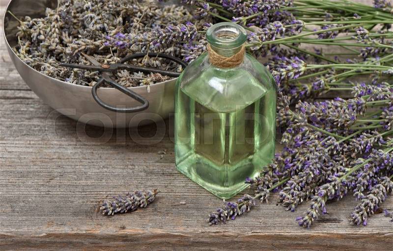 Lavender oil with fresh flowers on wooden background. Vintage style still life, stock photo