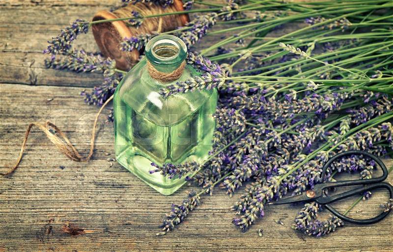 Herbal lavender oil with fresh flowers bouquet on wooden background. Country style still life. Vintage toned picture with vignette, stock photo