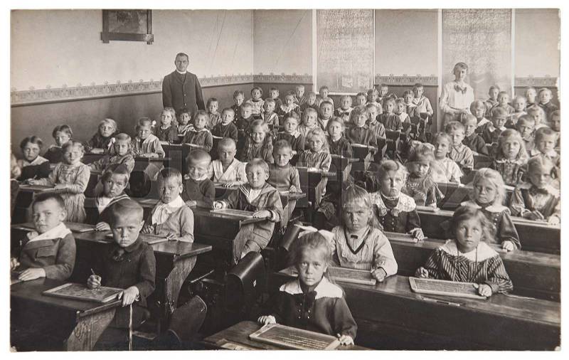 Group of children and teacher in the classroom. Retro picture of classmates in the school. Vintage photo with original film grain, blur and scratches from ca 1932 , stock photo