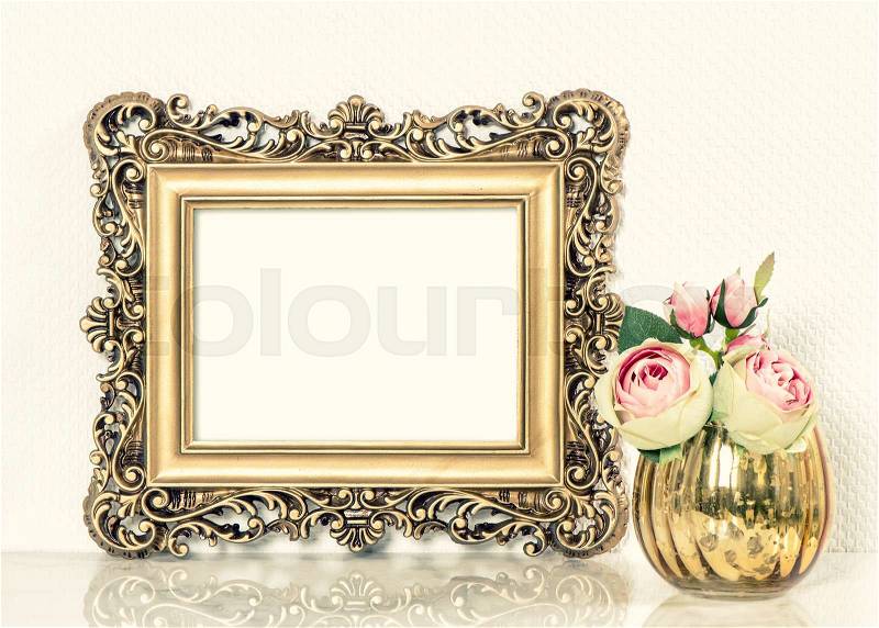 Golden baroque picture frame and roses flowers bouquet. Retro style mock up with space for your picture or text. Vintage toned photo, stock photo