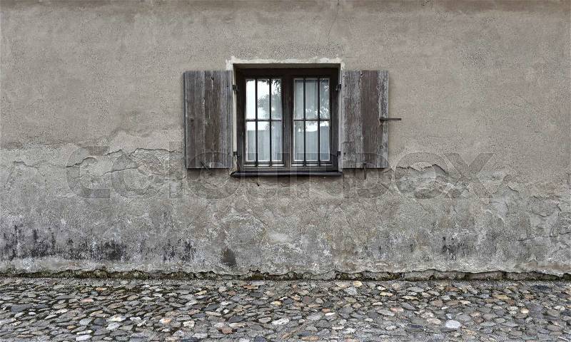 Weathered cracked wall with old wooden window. Stone texture background, stock photo