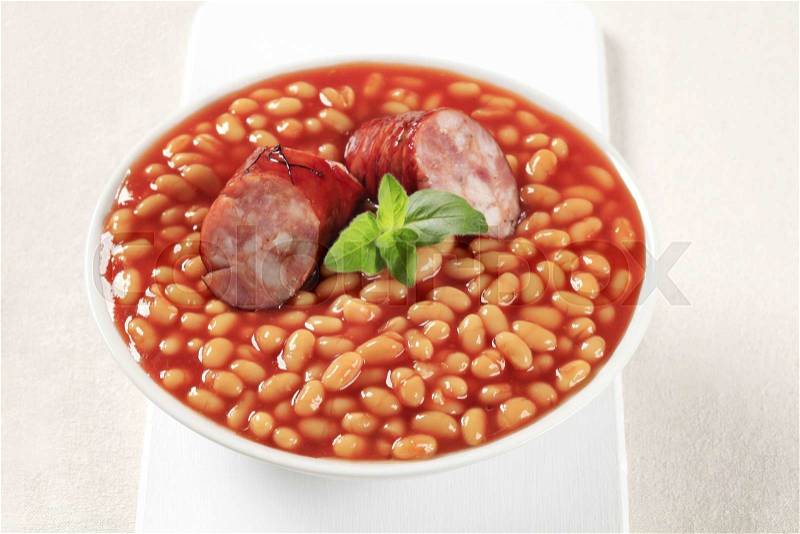Baked beans and sausage in a white bowl , stock photo