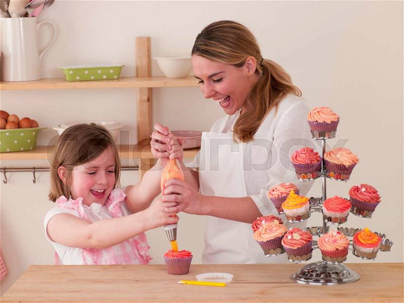 Mother and Daughter making cakes together, stock photo