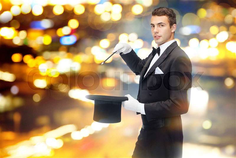 Performance, circus, show concept - magician in top hat with magic wand showing trick, stock photo