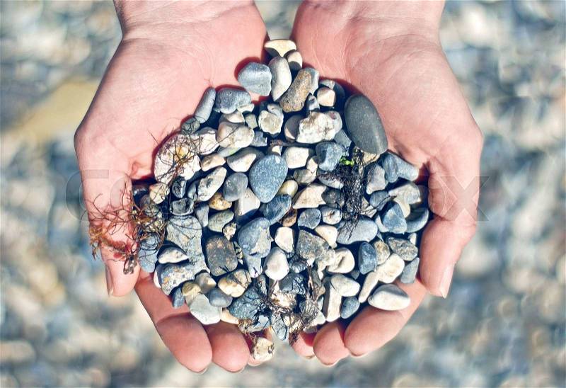 Handful of stones in hands, stock photo