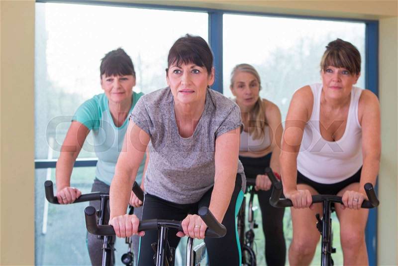 A group of senior women using spinning bikes at the gym, stock photo