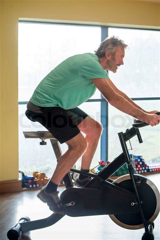 One senior man using a spinning bike at the gym, stock photo