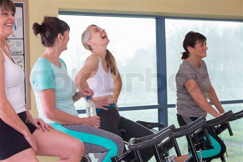 A group of senior women enjoying themselves on spinning bikes at the gym, stock photo