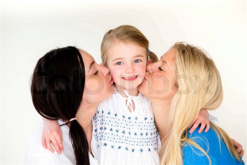 Same sex couple kissing eitherside of their daughters face for the camera, stock photo